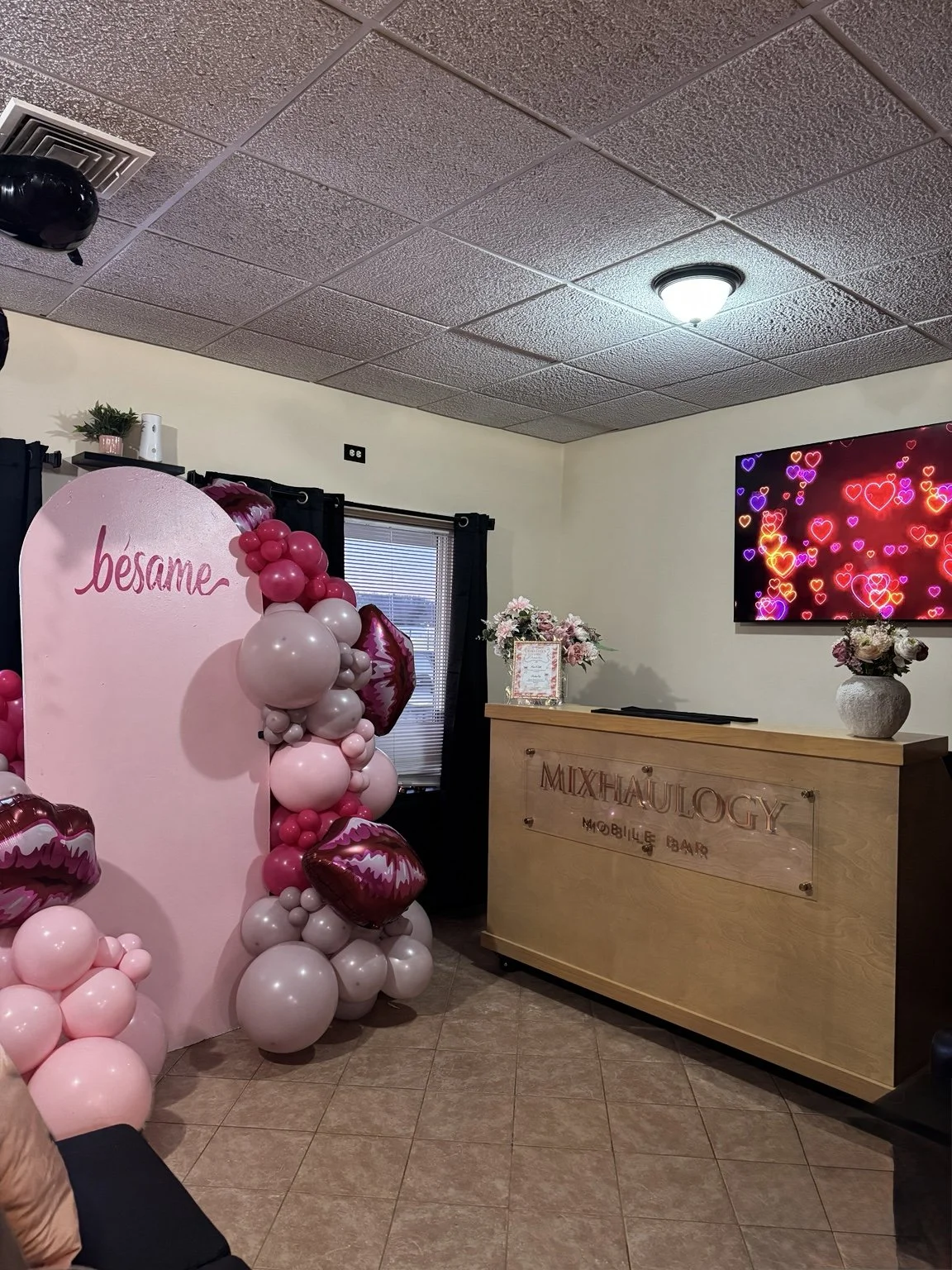 Mixhaulogy portable bar at an indoor celebration with a pink balloon display