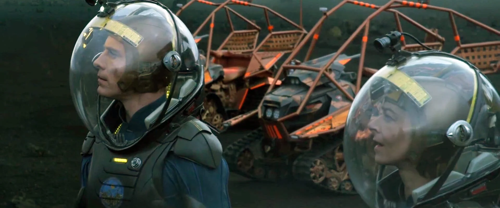 Shaw and a crewmate in EVA helmets with rovers in the background