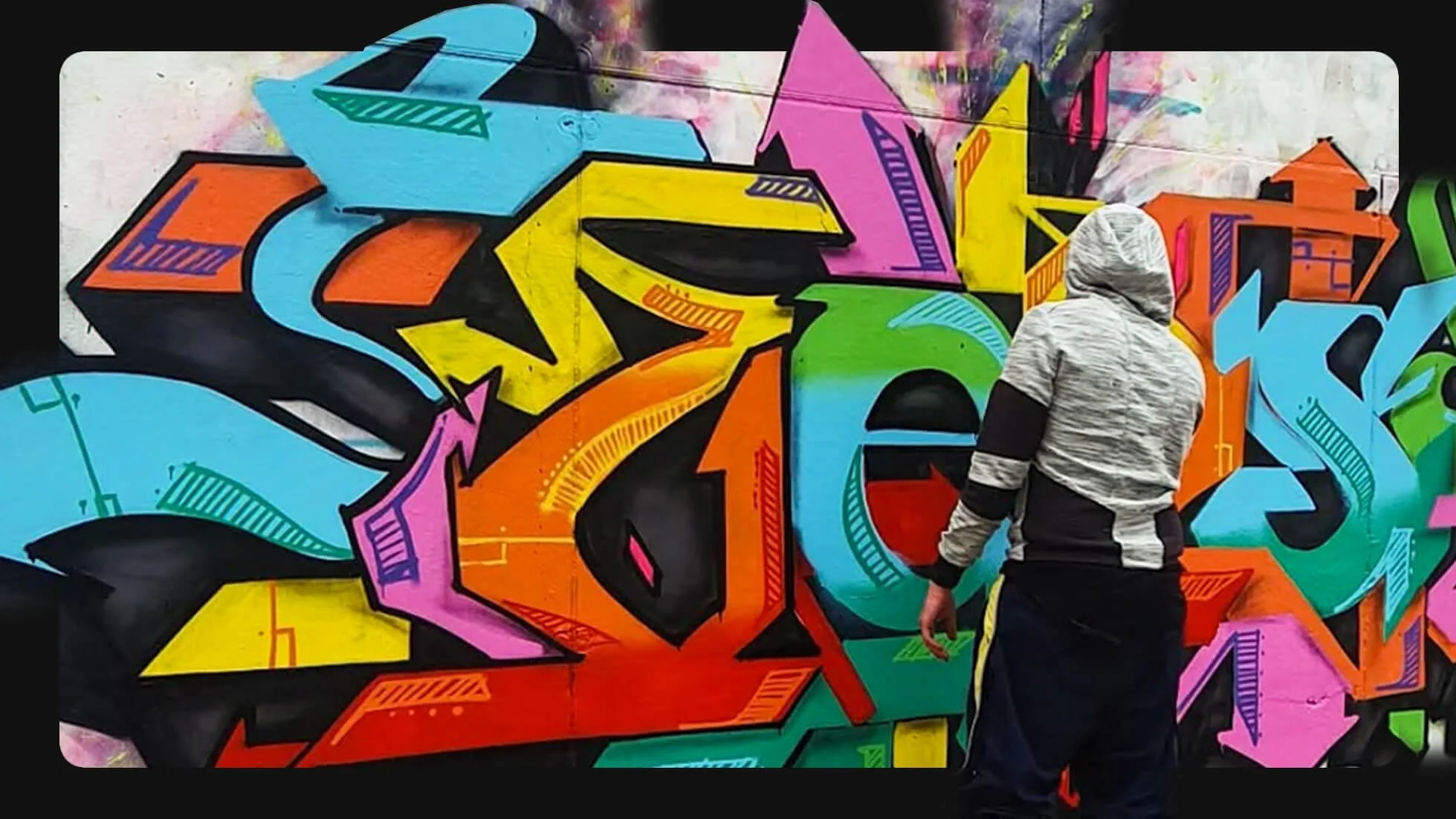 TKL 137 stands in front of a vivid, multilayered graffiti mural.