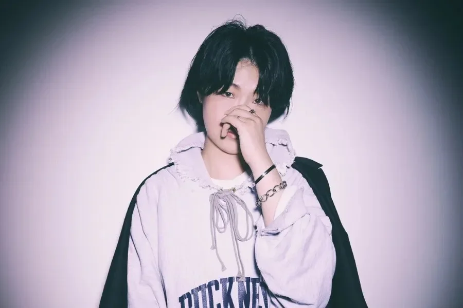 A Death Note performer in a white hooded top singing into a microphone