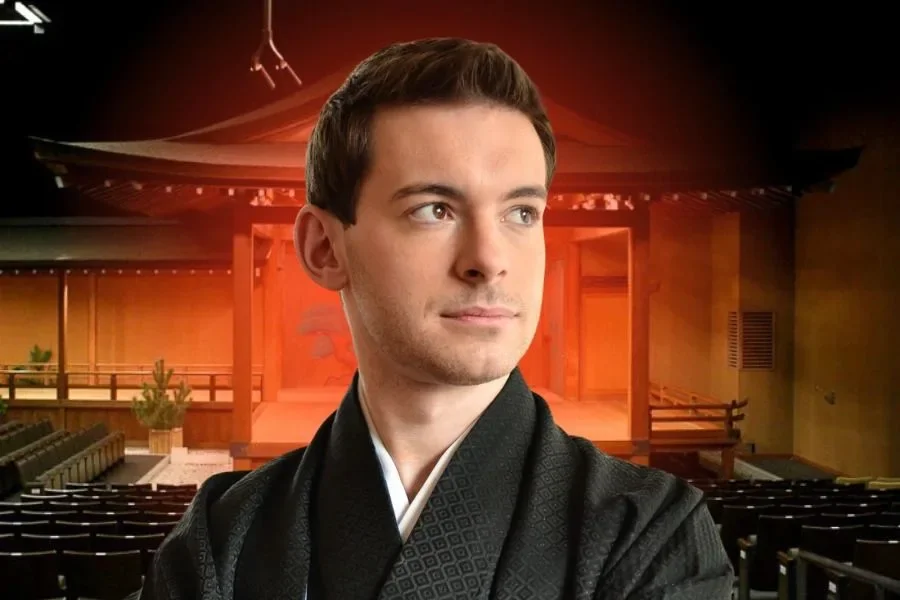 Sébastien Moncus, founder of My Taiken, in a black kimono in front of a Noh stage lit in red