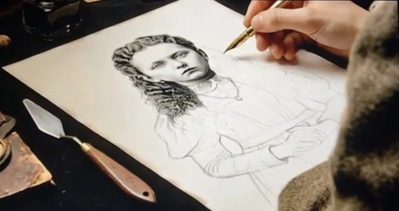 A hand drawing a portrait in pen and ink