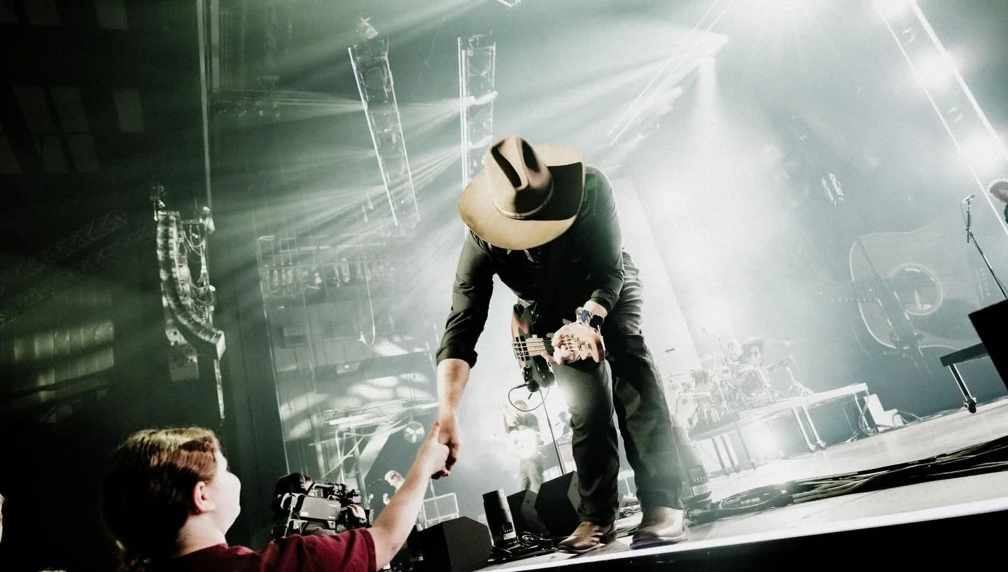 Tai Anderson leaning off the stage mid-show to shake hands with a young fan in the front row