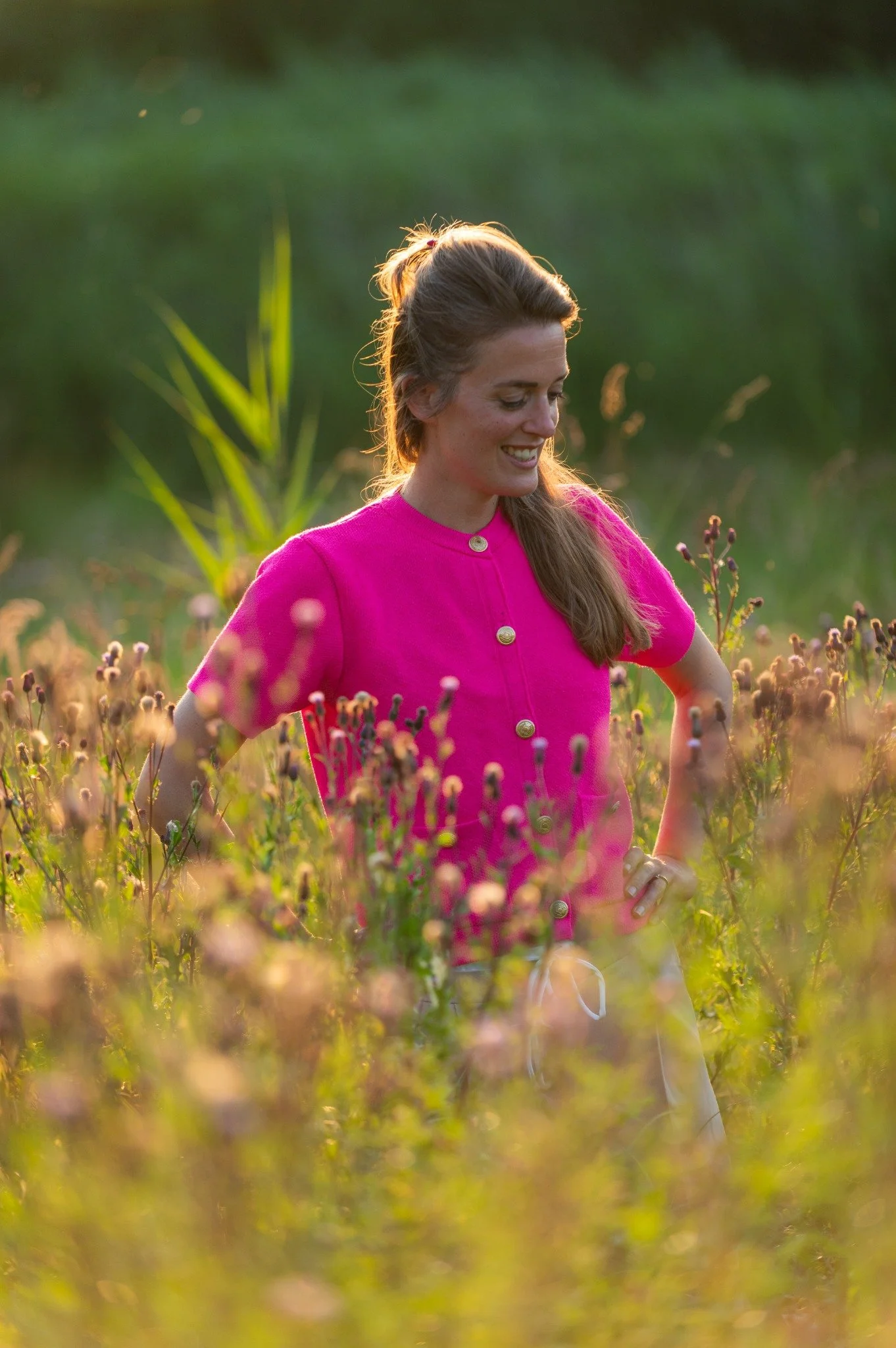 Fieke de Goede in een roze shirt tussen de bloemen, in warm zonlicht