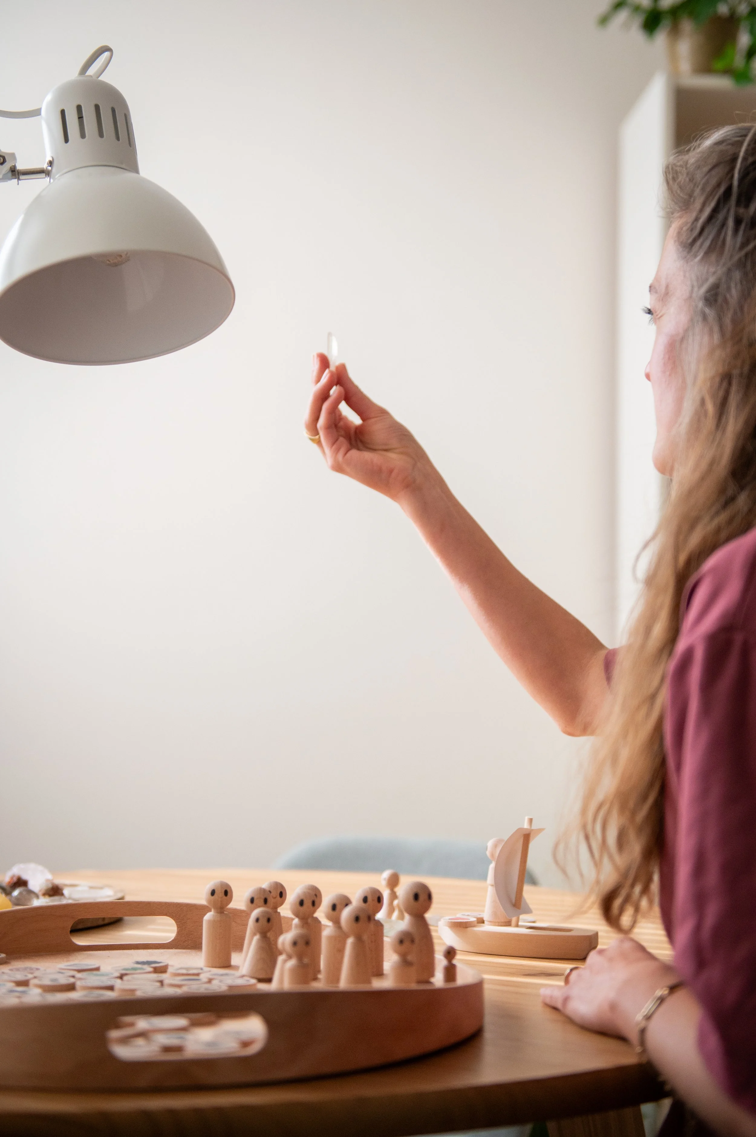 Fieke werkt aan de praktijktafel met een biotensor en houten figuren