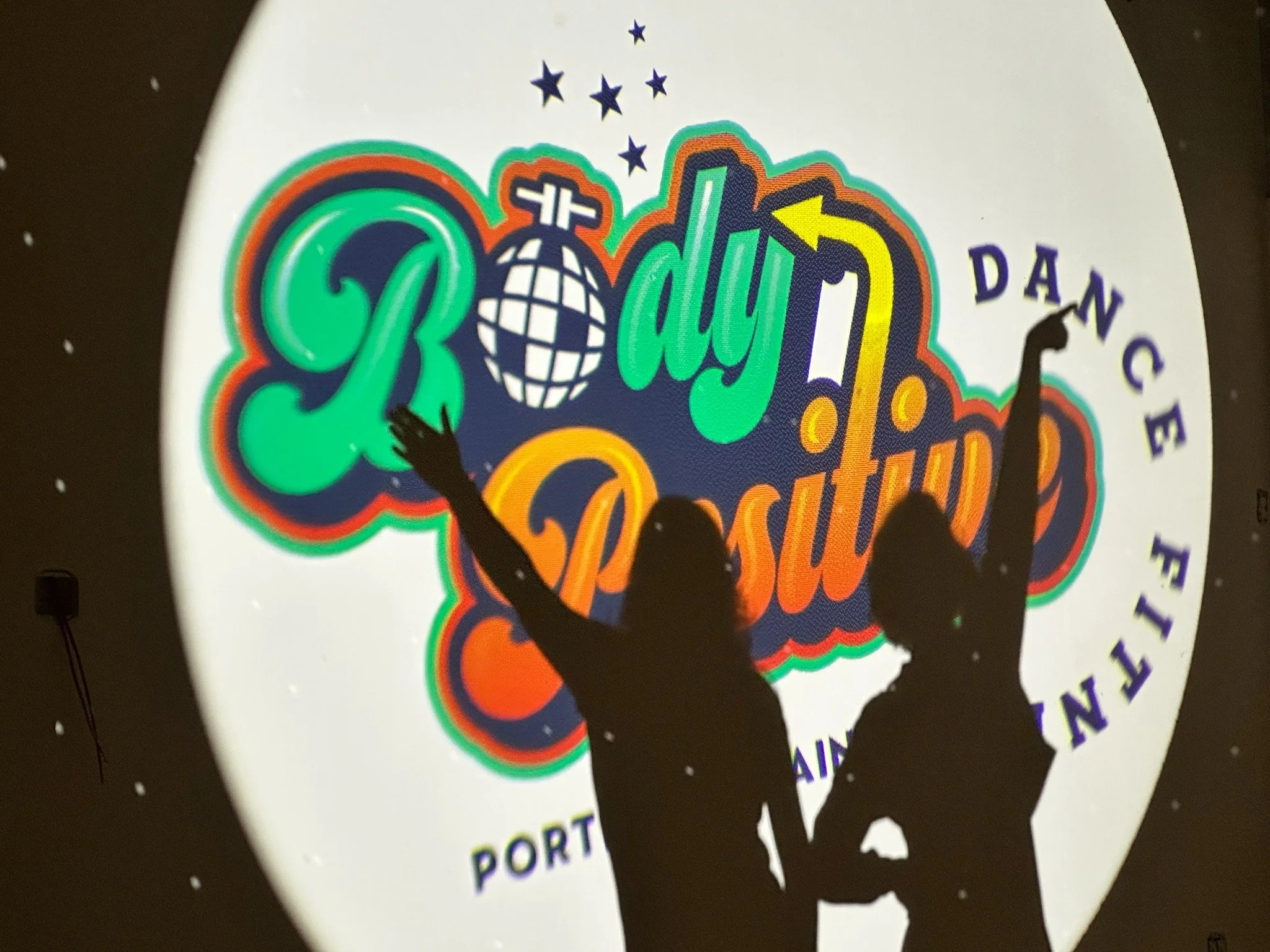 BPDF co-owners Carson and Erin dancing in silhouette in front of the studio logo