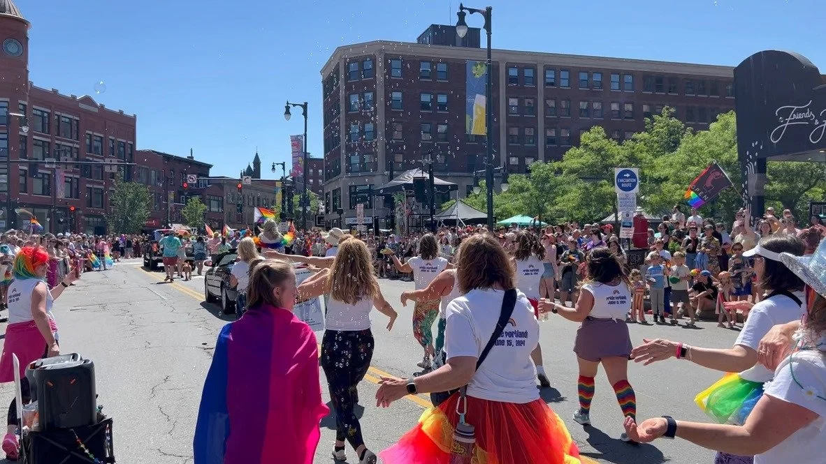 BPDF parade participants dancing together along a crowd-lined Portland street