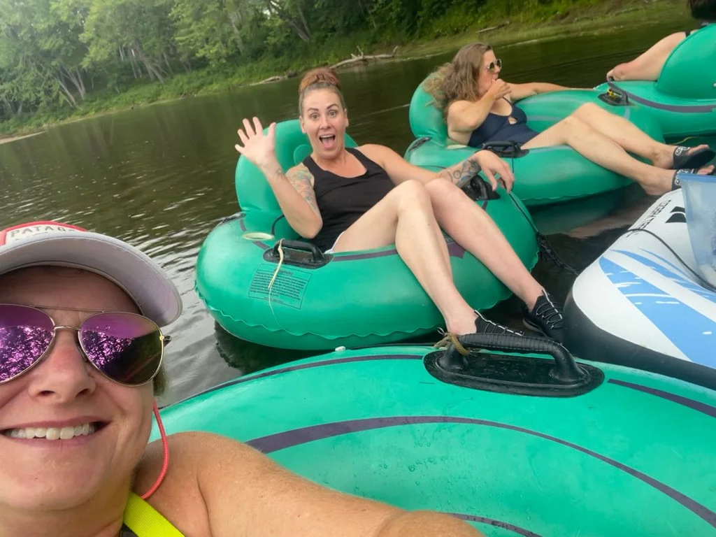 Studio friends smiling together in green tubes on a river