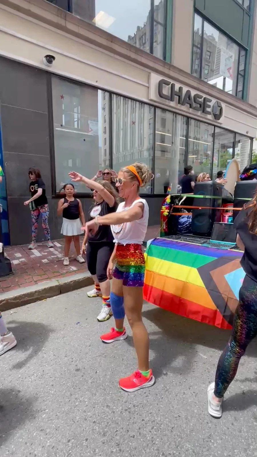 A BPDF parade participant dancing beside a rainbow flag