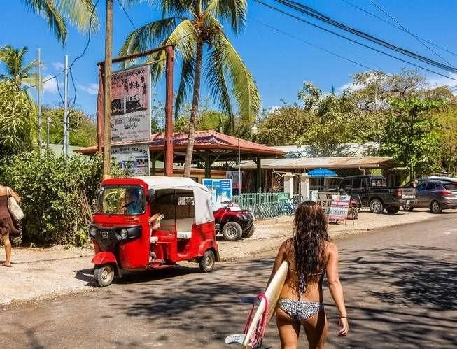 a tuk-tuk carrying a surfboard