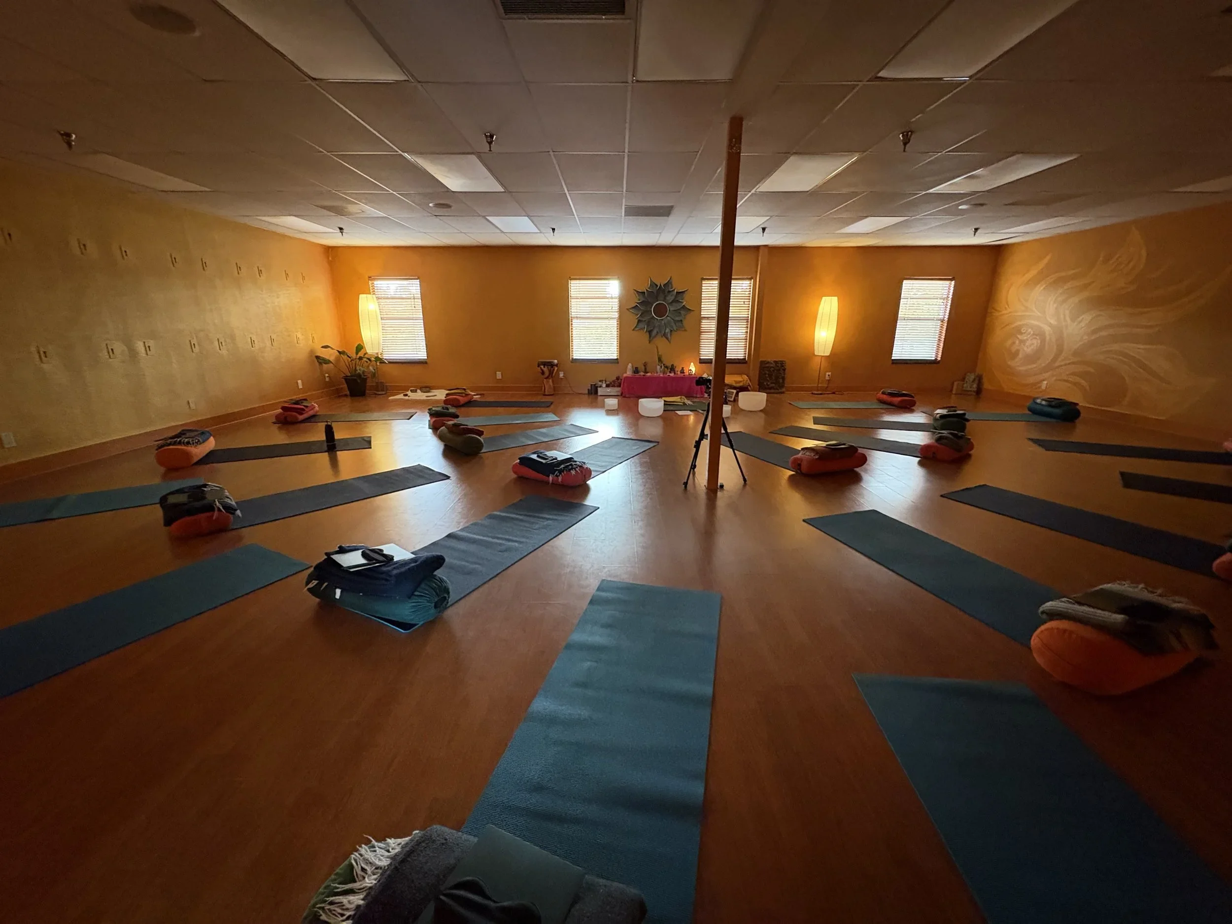 Yoga mats and cushions arranged across a warmly lit gathering room.