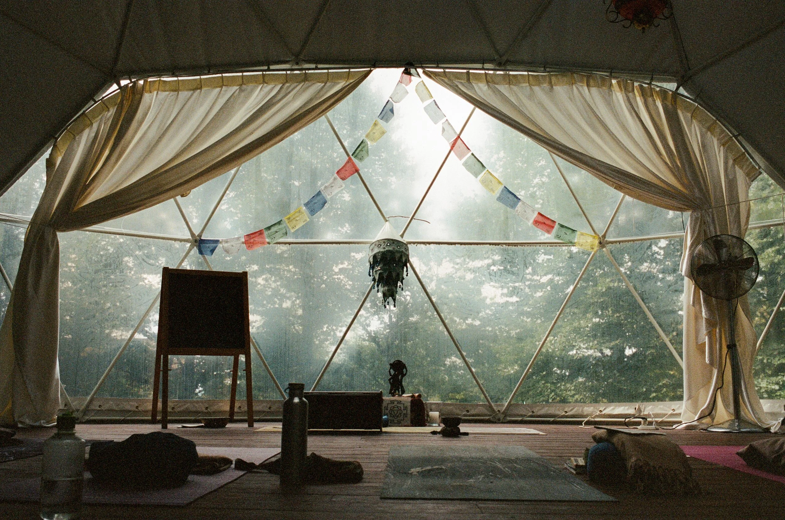 An open-air retreat pavilion surrounded by palms, with people resting together on yoga mats