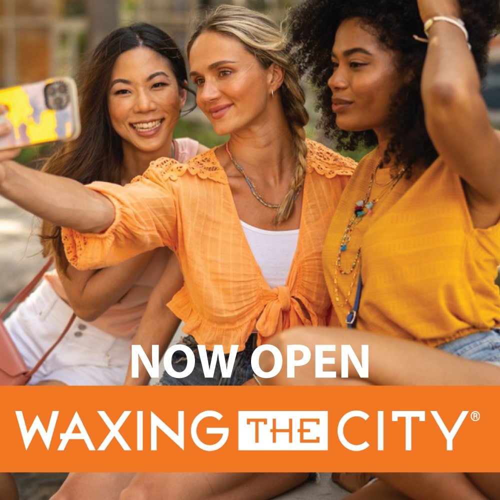 Three women posing for a photo holding their phone in front of them. There is text saying Now Open, waxing the city.