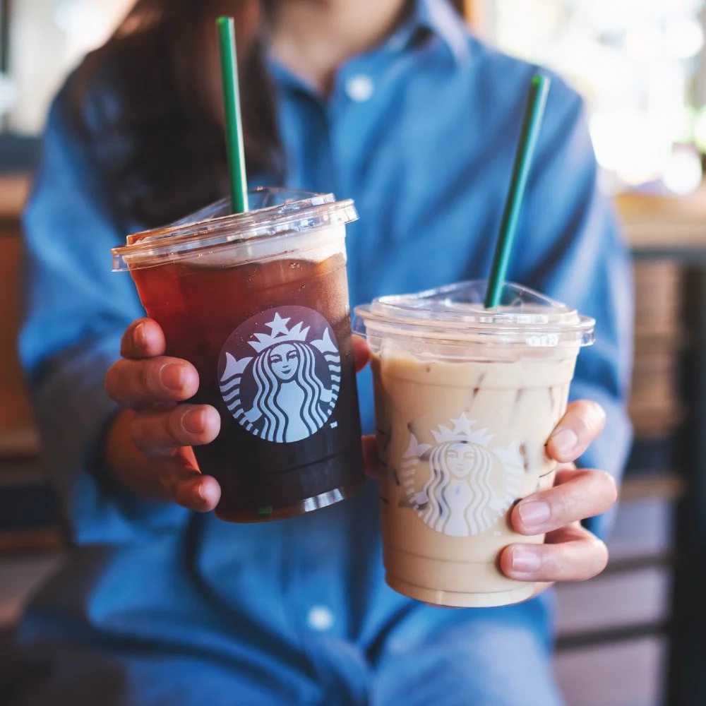 Customer holding two iced Starbucks beverages at Pleasanton Gateway Shopping Center.