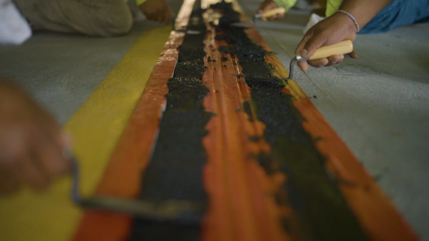 Close-up of a worker’s hands sealing an expansion joint during construction