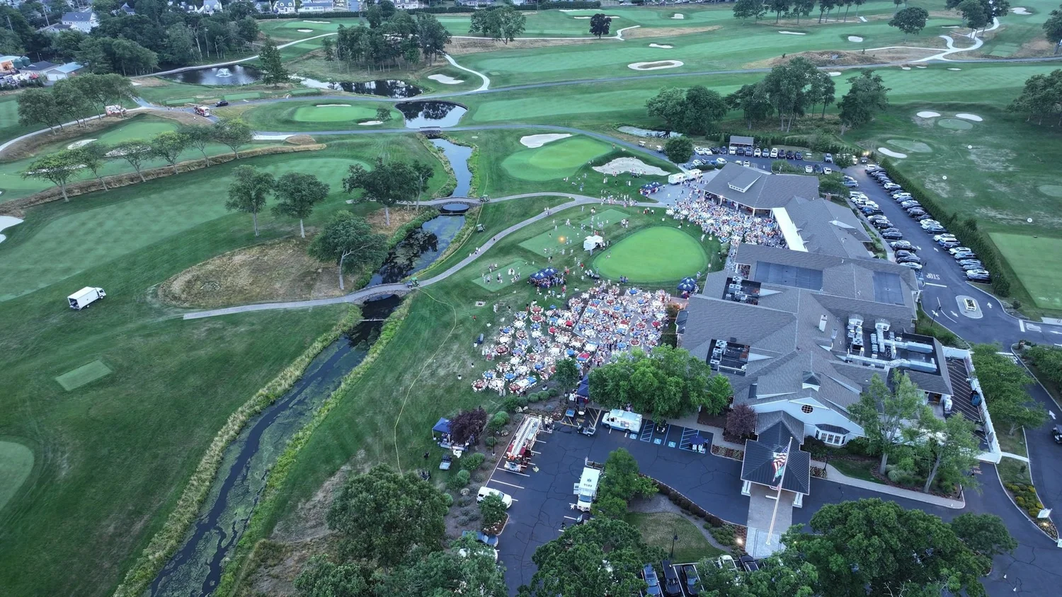Drone aerial of a clubhouse and grounds with members gathered on the lawn