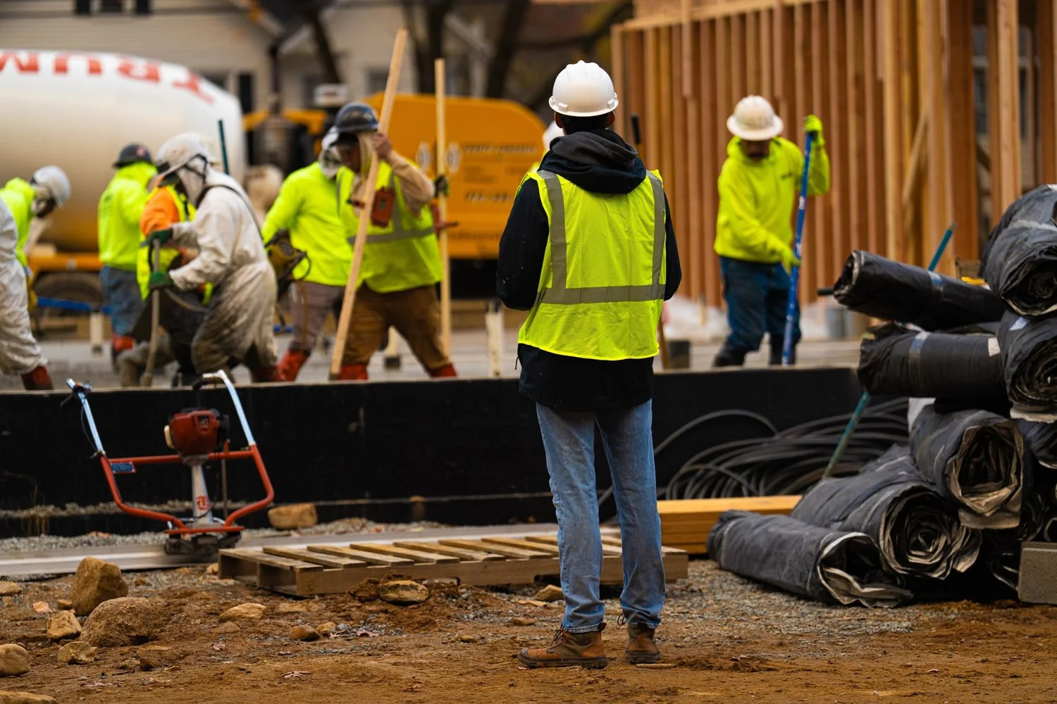 Videographer filming a concrete pour with the crew and a mixer truck around him
