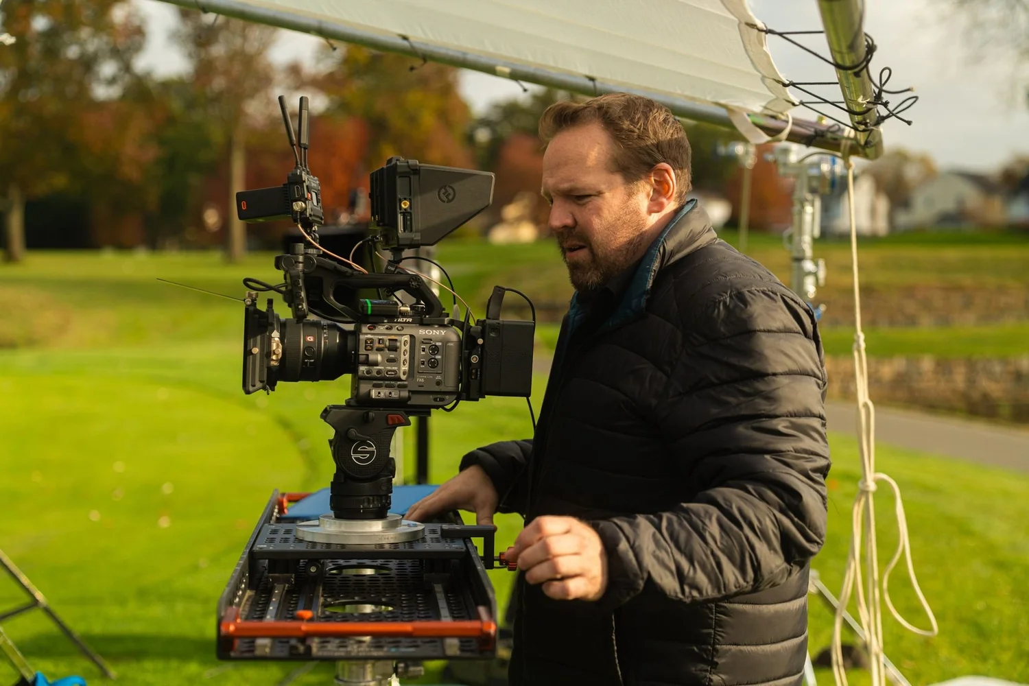 Camera operator checking a cinema camera monitor during a shoot on a golf course