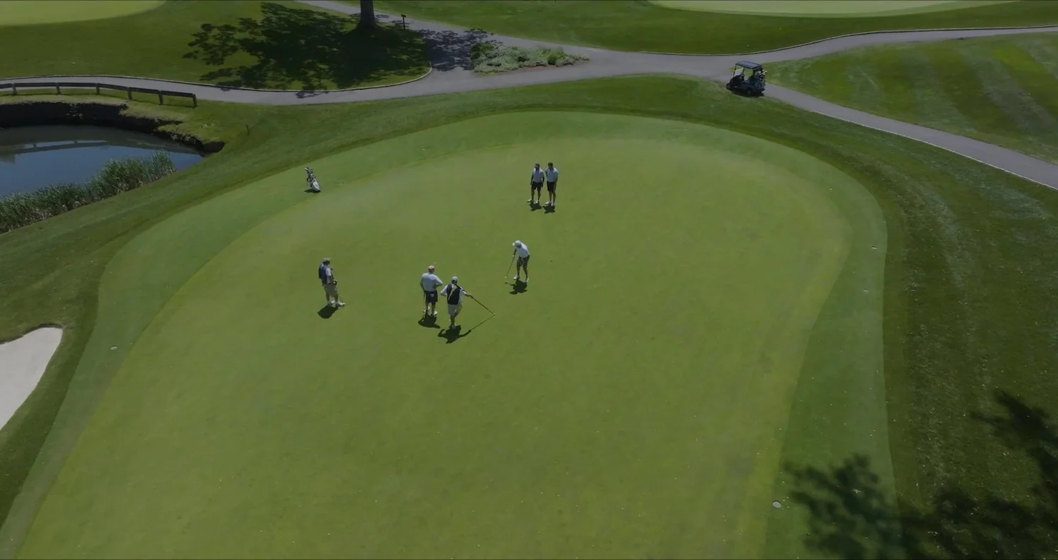 Top-down drone shot of golfers on a green at a private golf club