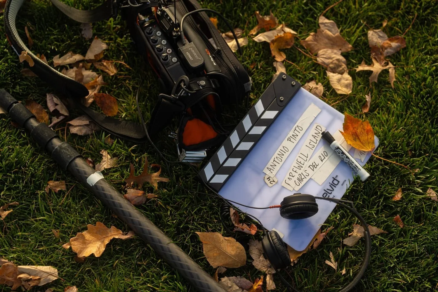 Film slate, headphones and boom pole on autumn leaves, prepped from a video production brief