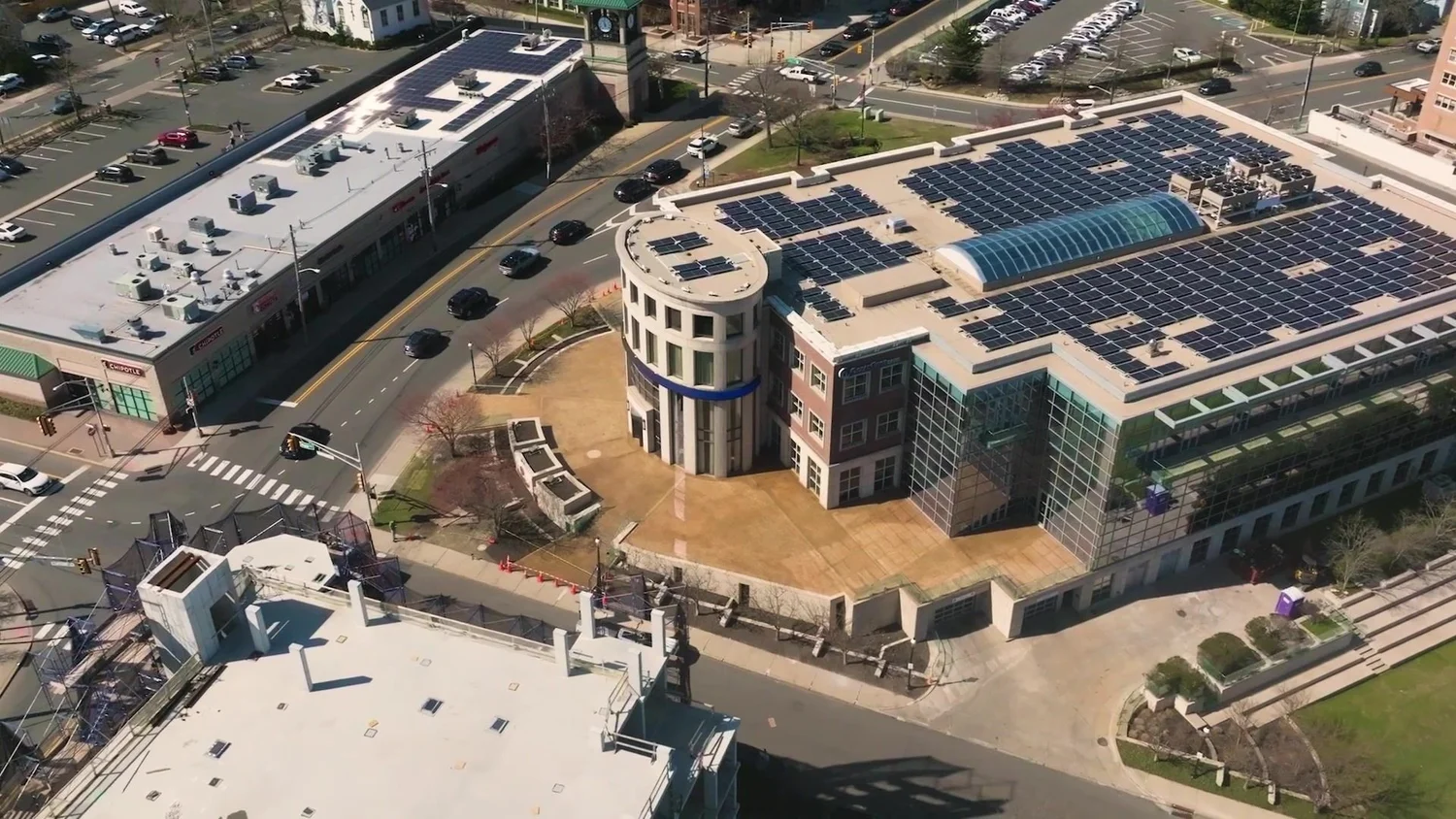 Drone aerial of a finished multi-story office building with rooftop solar panels in a town center