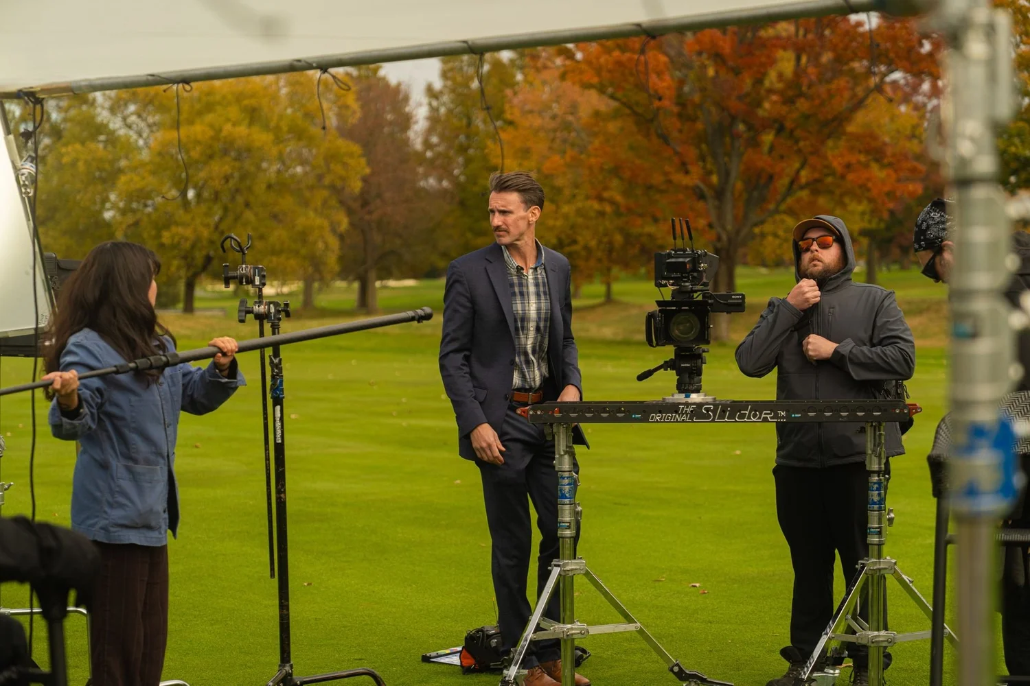 Film crew adjusting a camera slider during a shoot on a golf course
