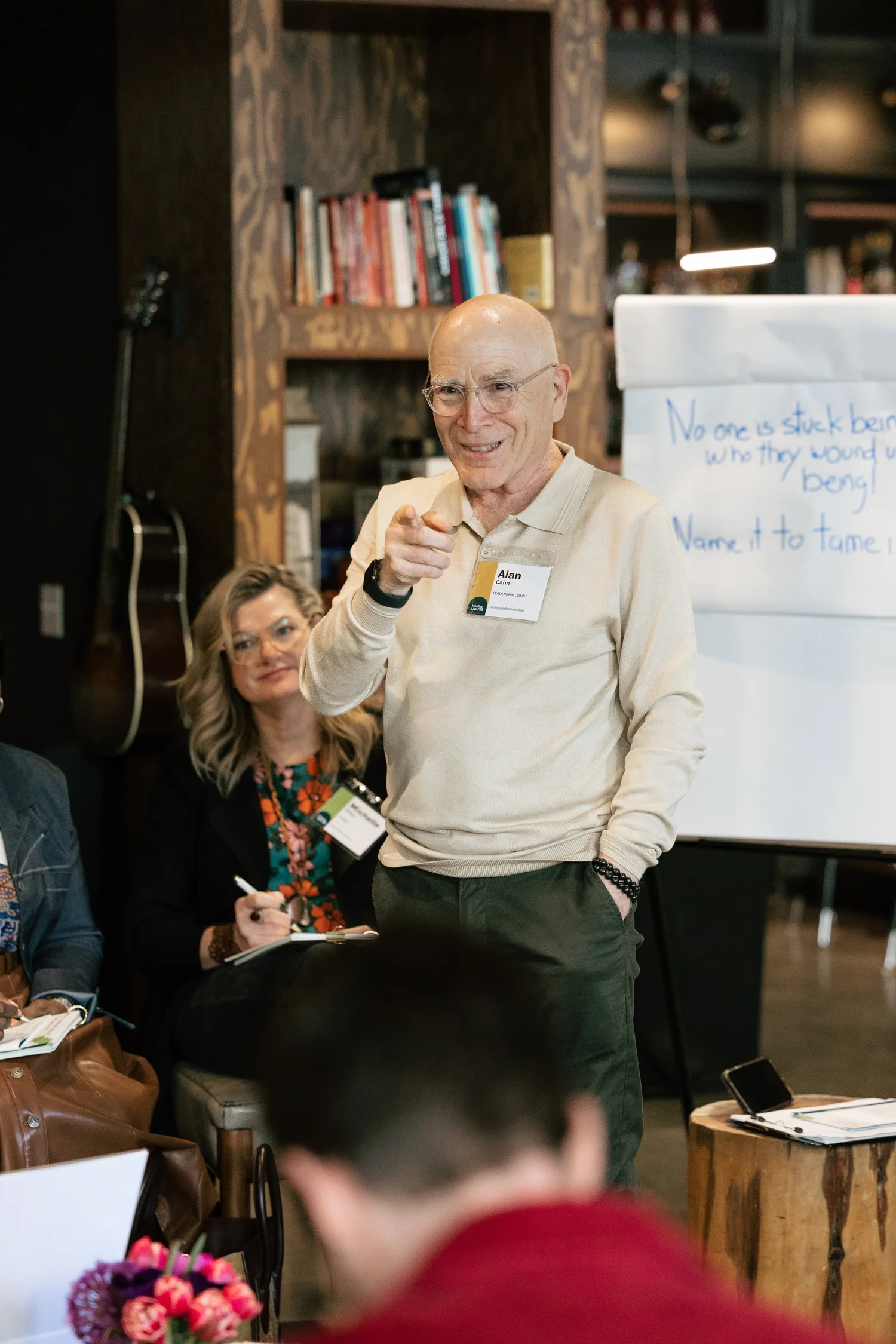 A Henley facilitator standing and smiling as he leads a workshop for a group of leaders