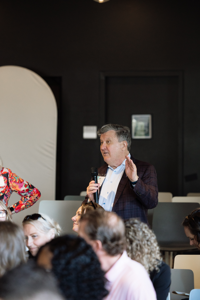 A man speaking into a microphone to a seated audience at a Henley event