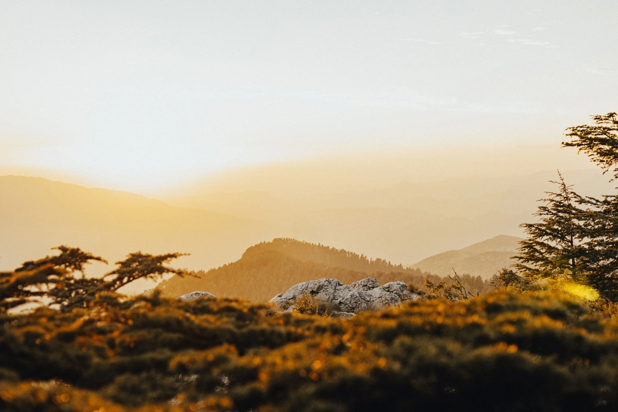Mountain range illuminated by the setting sun above rolling green hills