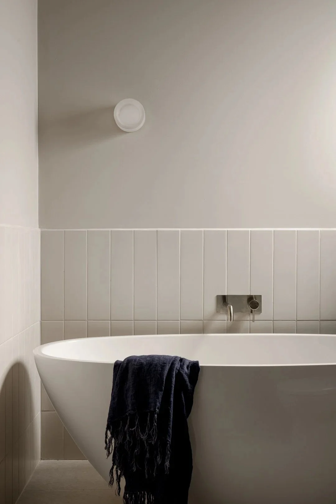 Freestanding bath against white vertical tiles