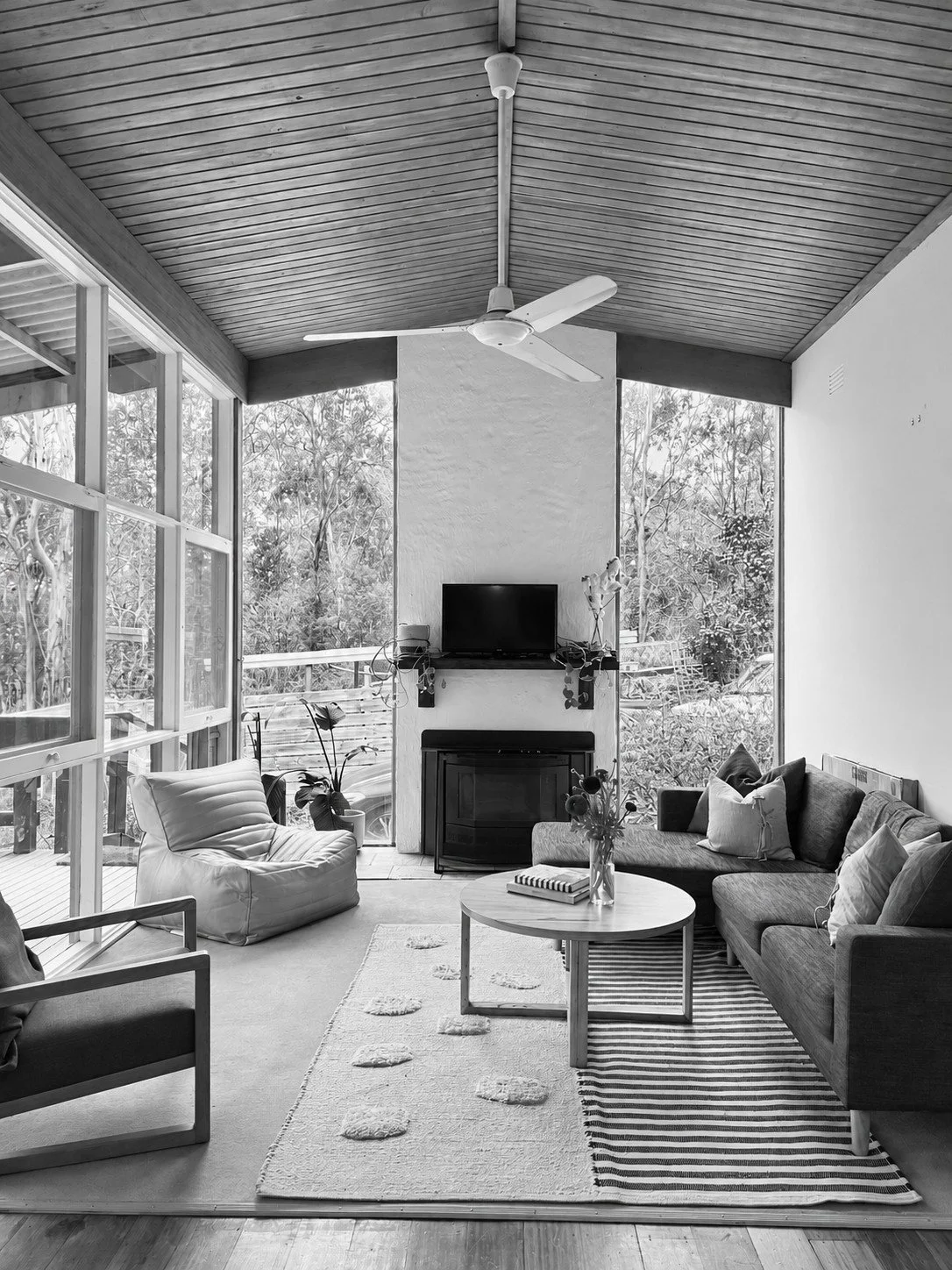 Before: the living room with its wall of glass, timber-lined ceiling and fireplace