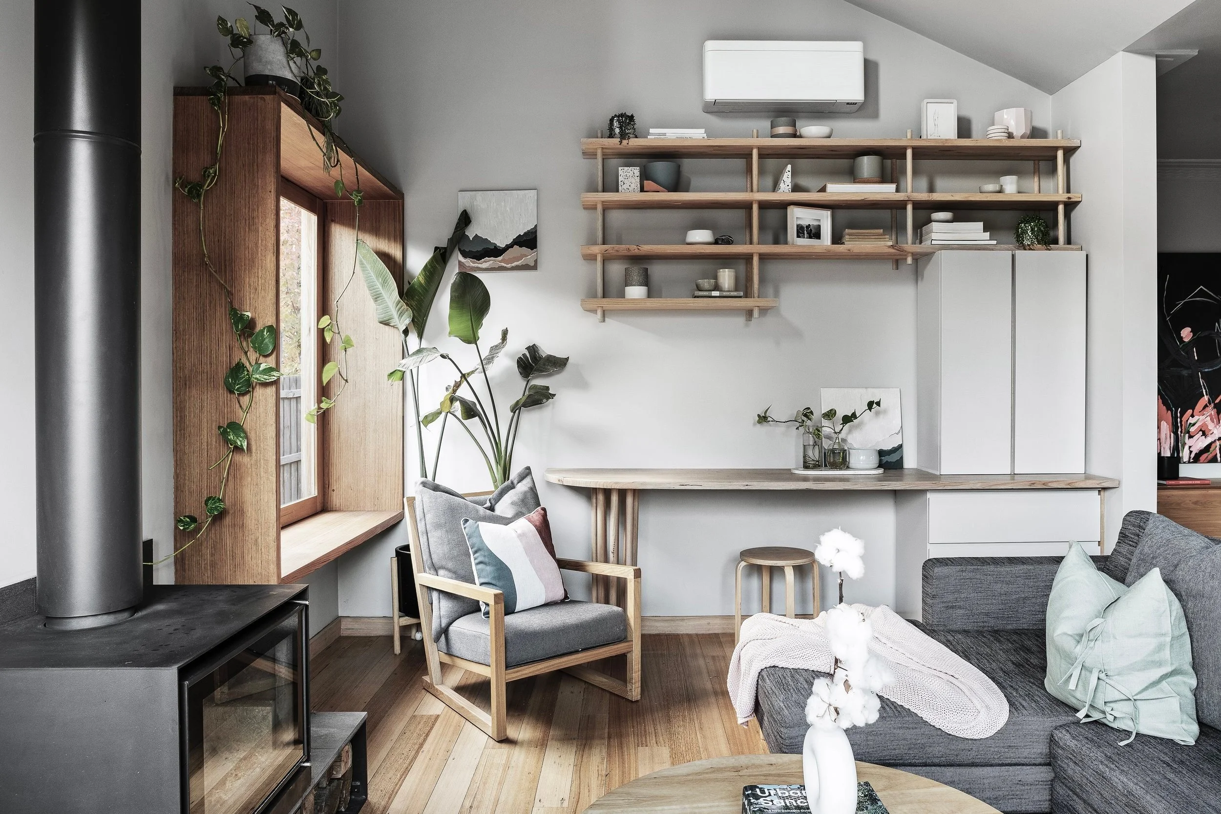 Living area under the vaulted ceiling, with a wood heater, timber shelving and built-in joinery