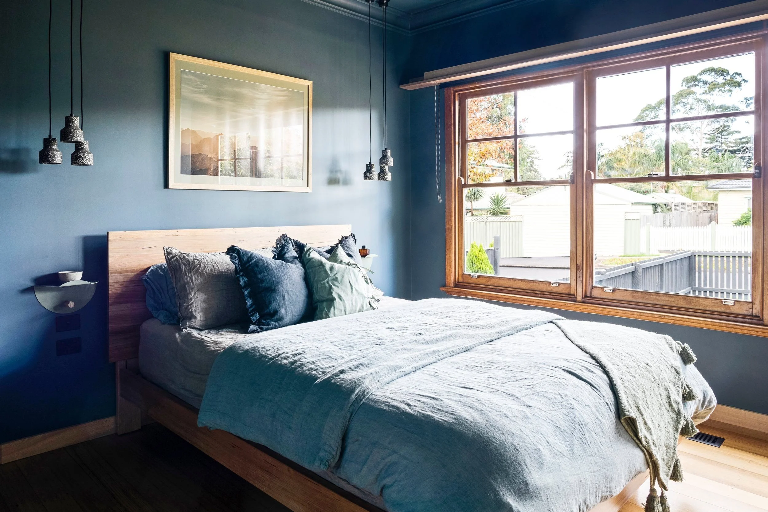 Bedroom painted deep blue with a timber bed and blue linen