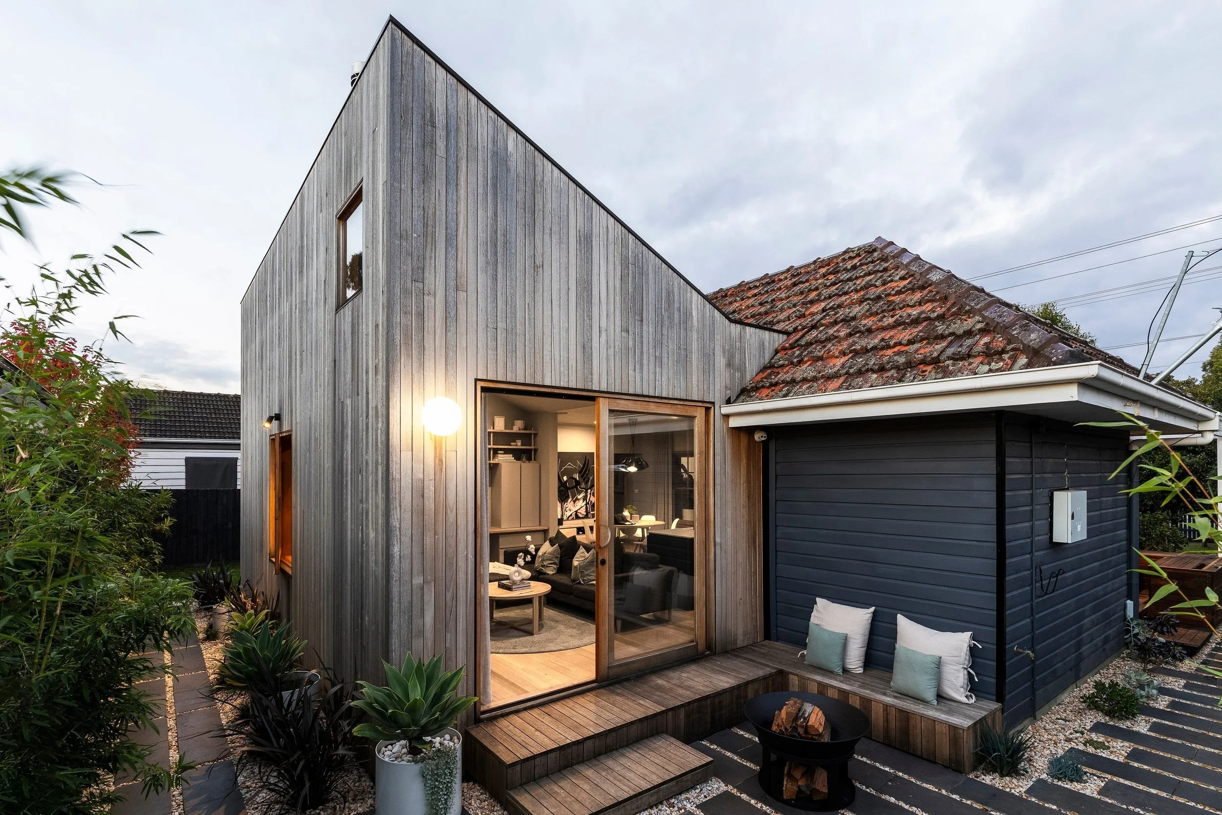 Adeline House: a gabled rear addition in silvered vertical timber beside the original dark weatherboard house
