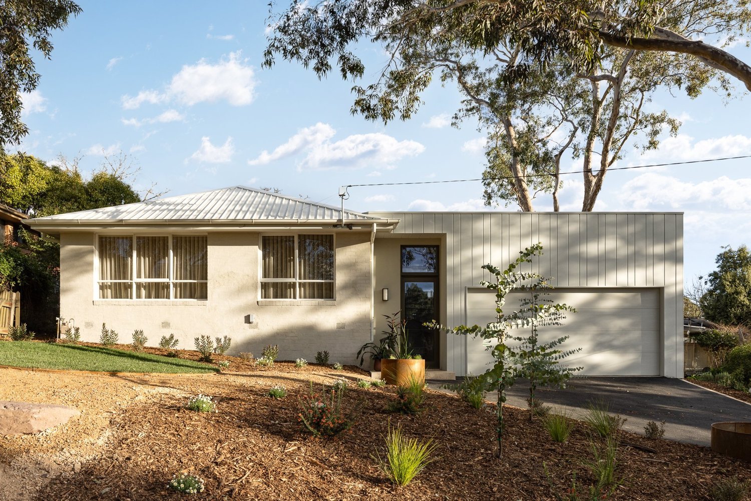 Garden House street front: bagged brick, a new clad garage and a tall entry door