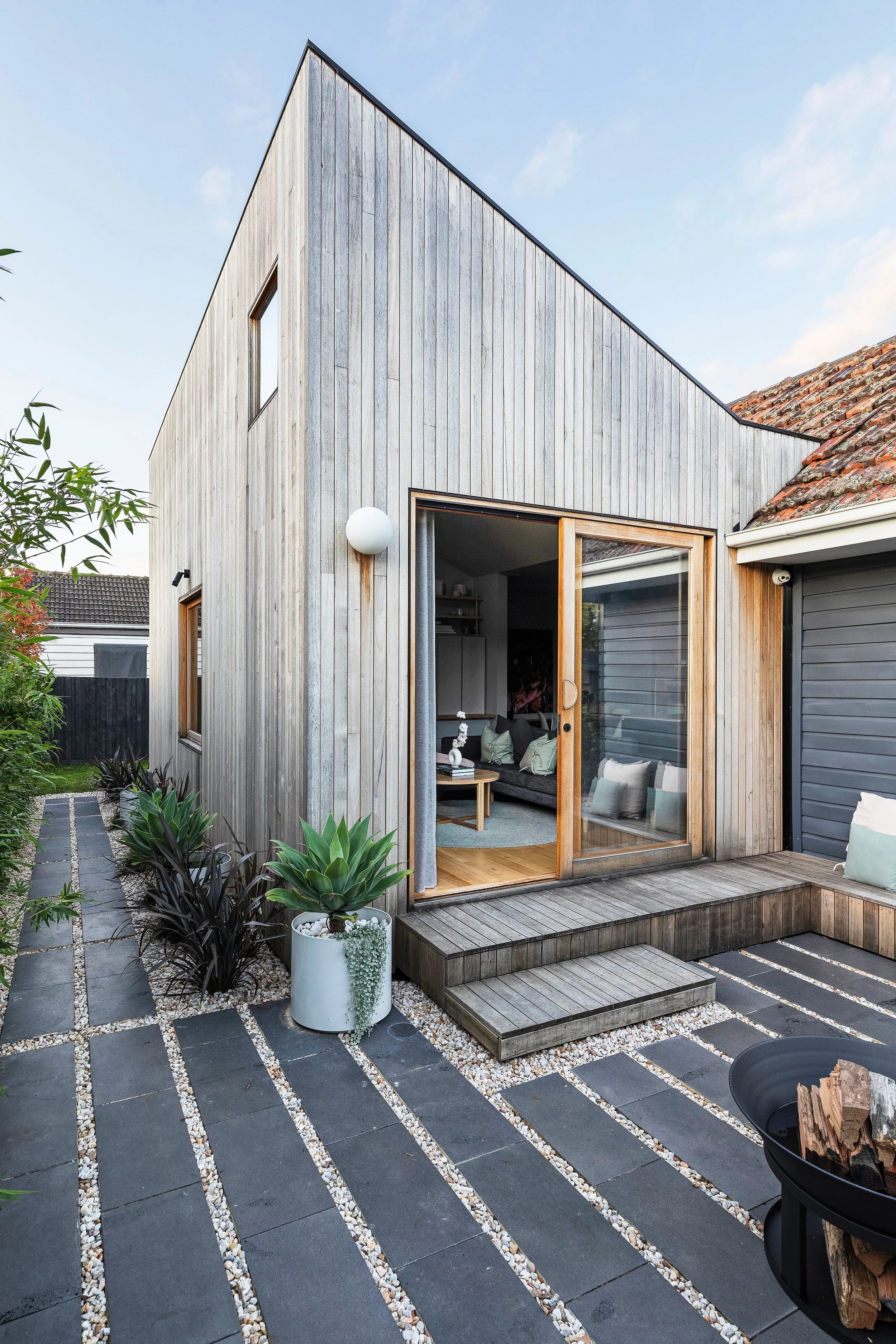 Rear extension clad in vertical McCormack timber, with a glazed door to a paved courtyard