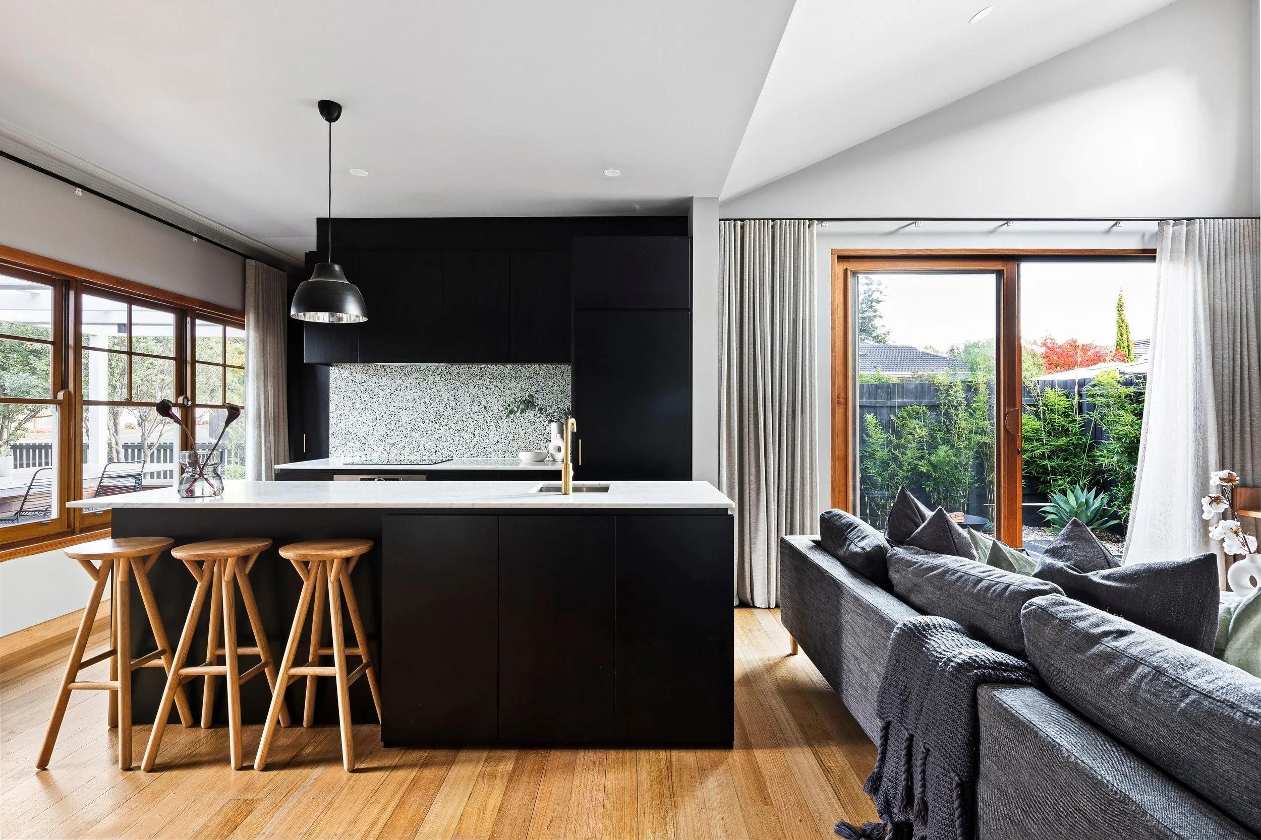 Kitchen with a black island, timber stools and a glazed door to the garden