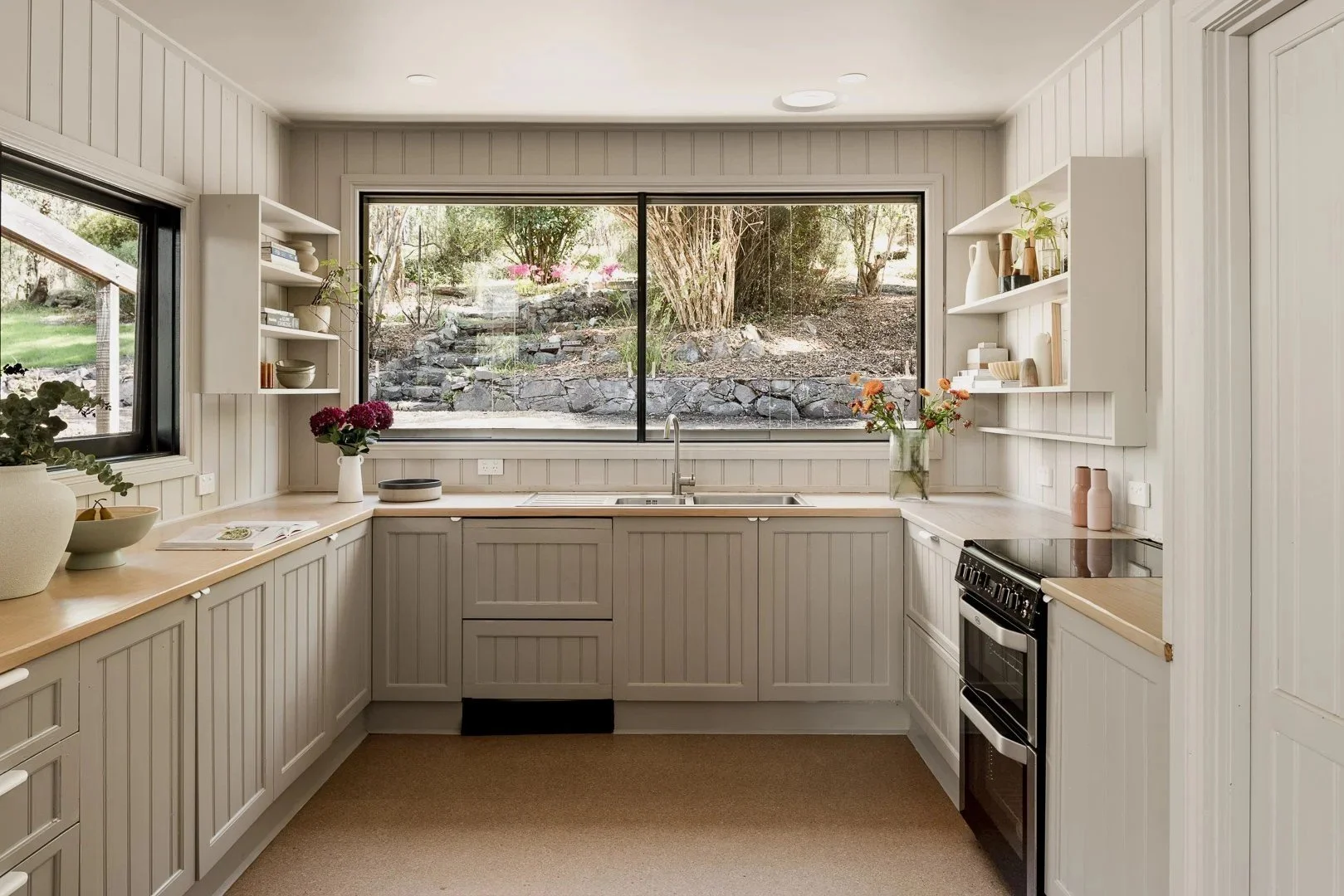 U-shaped kitchen in soft white with a window to the bush and open shelves