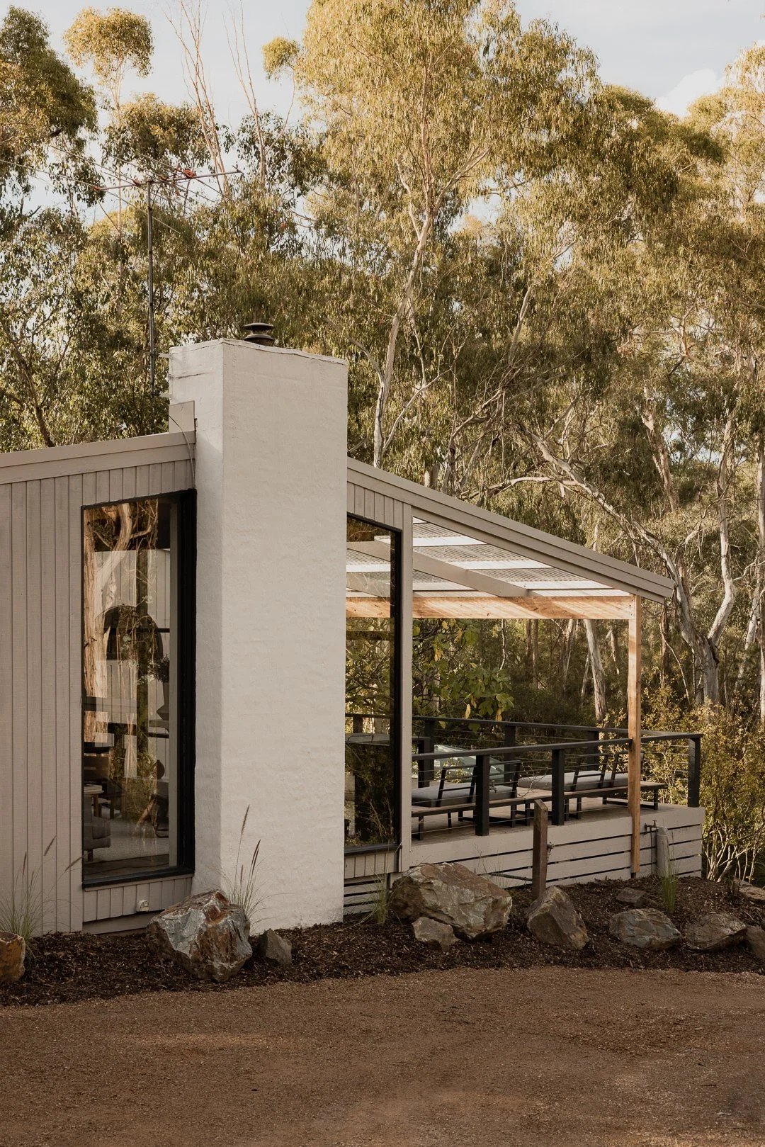 The white chimney and black-framed windows beside the covered outdoor room