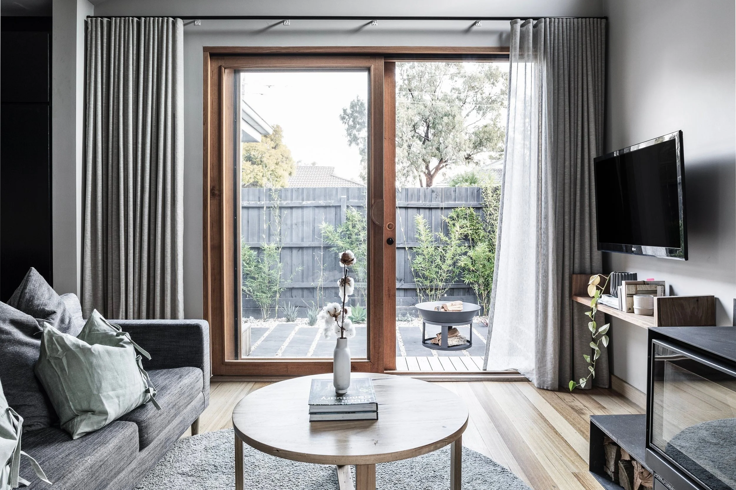 Living room with a grey sofa and a glazed door to the courtyard