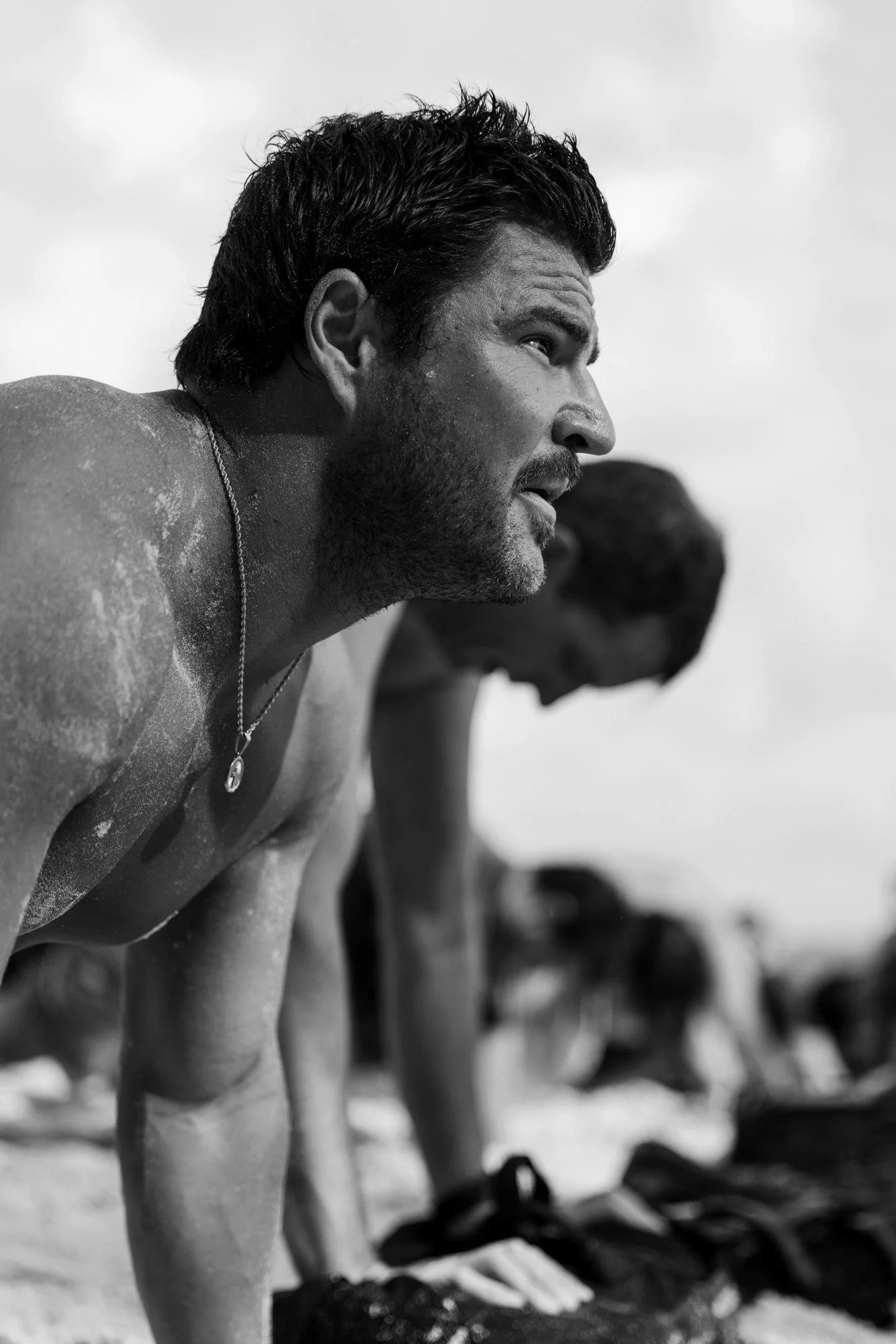 Two shirtless men training together on a beach