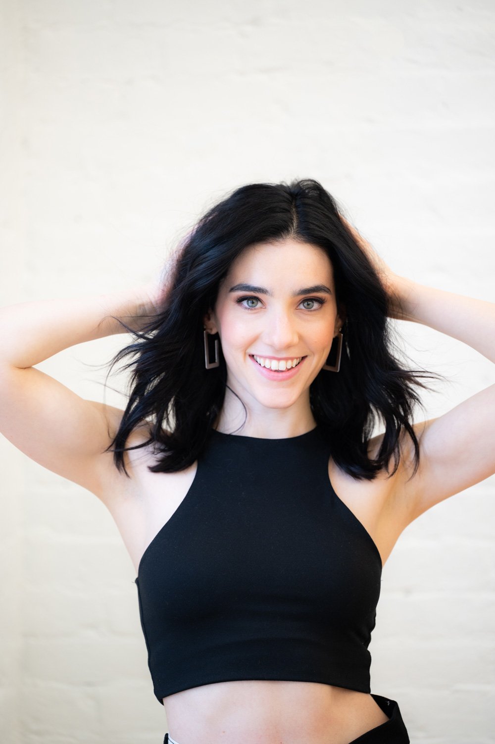 Headshot of Morgan Occhicone. She stands looking at the camera with her hands behind her head. She is smiling and has shoulder-length black hair, fair skin, and blue eyes.