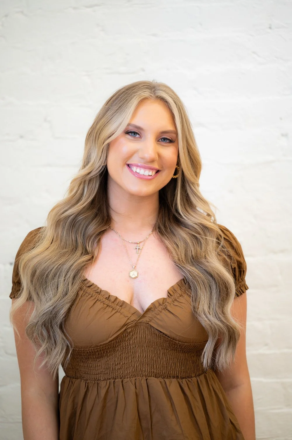 Headshot of Adaija Devivo. She is looking at the camera and smiling. She wears a brown ruffled top and has very long blonde, wavy hair. He skin is tan and she has blue eyes.