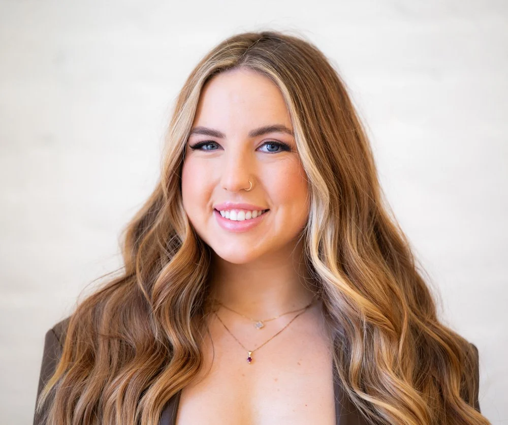 Headshot of Allison Arcard. She has fair skin, blue eyes, long, dirty-blonde wayv hair and smiles directly at the camera.