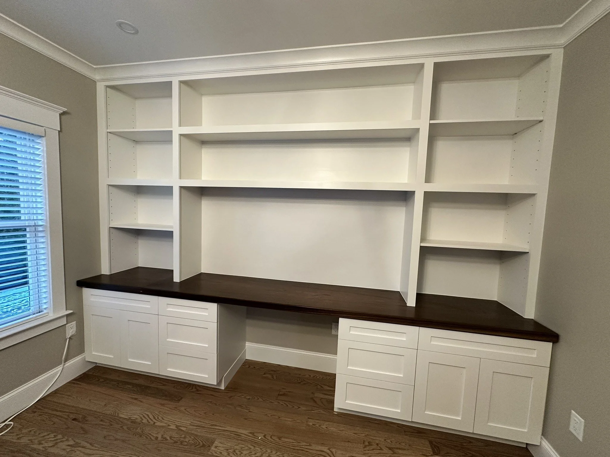 Custom built-in desk with dark wood top, white cabinetry and shelving