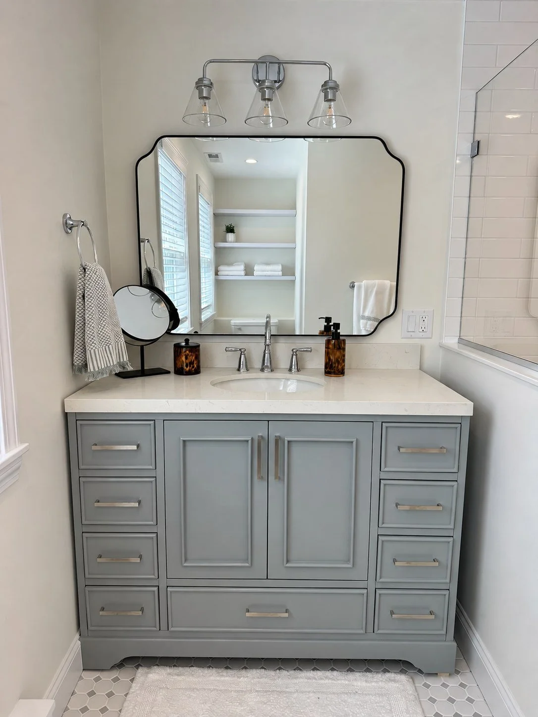 Gray vanity, framed mirror and chrome lighting