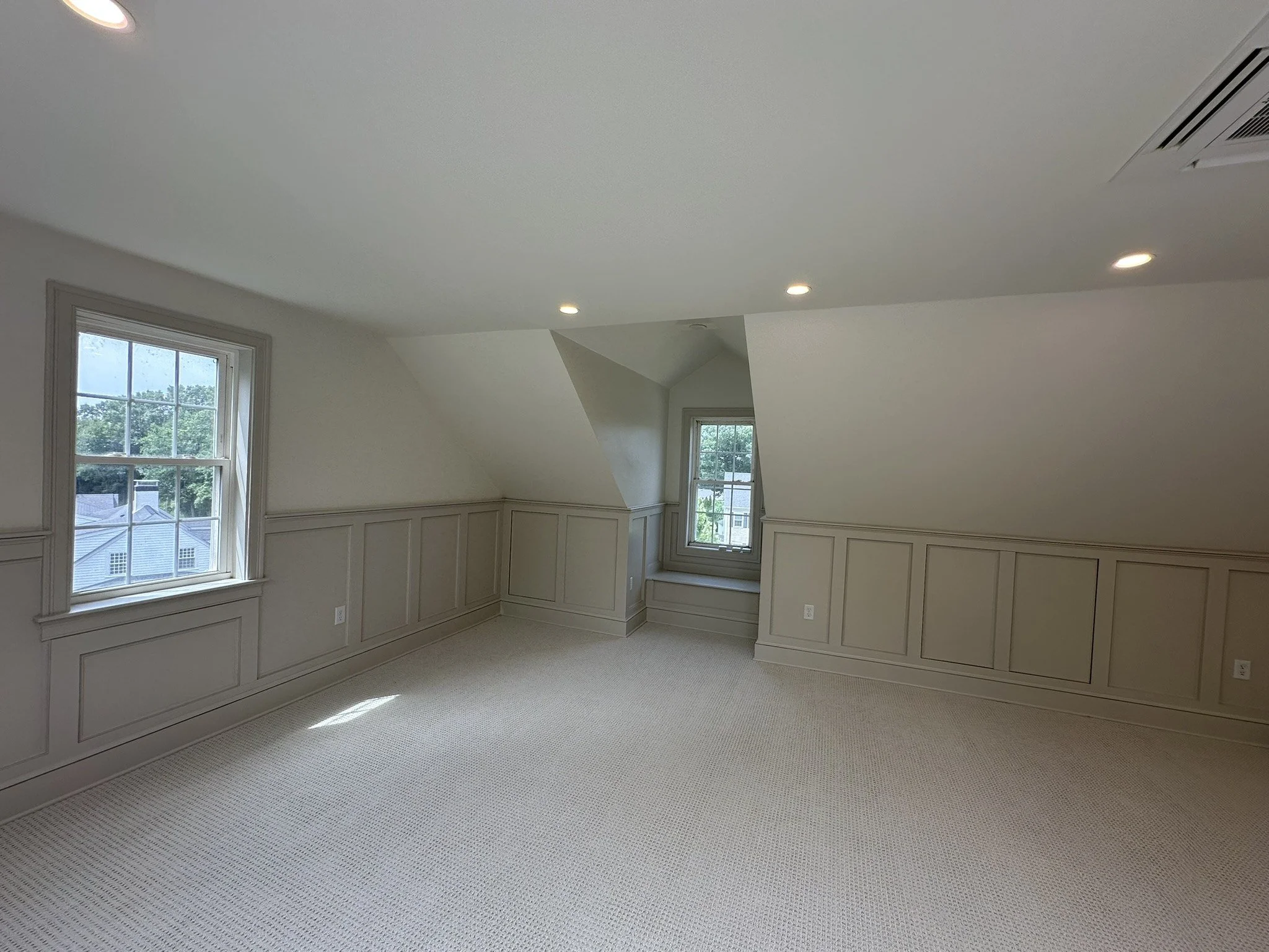 Opposite side of a finished attic with windows and paneled knee walls