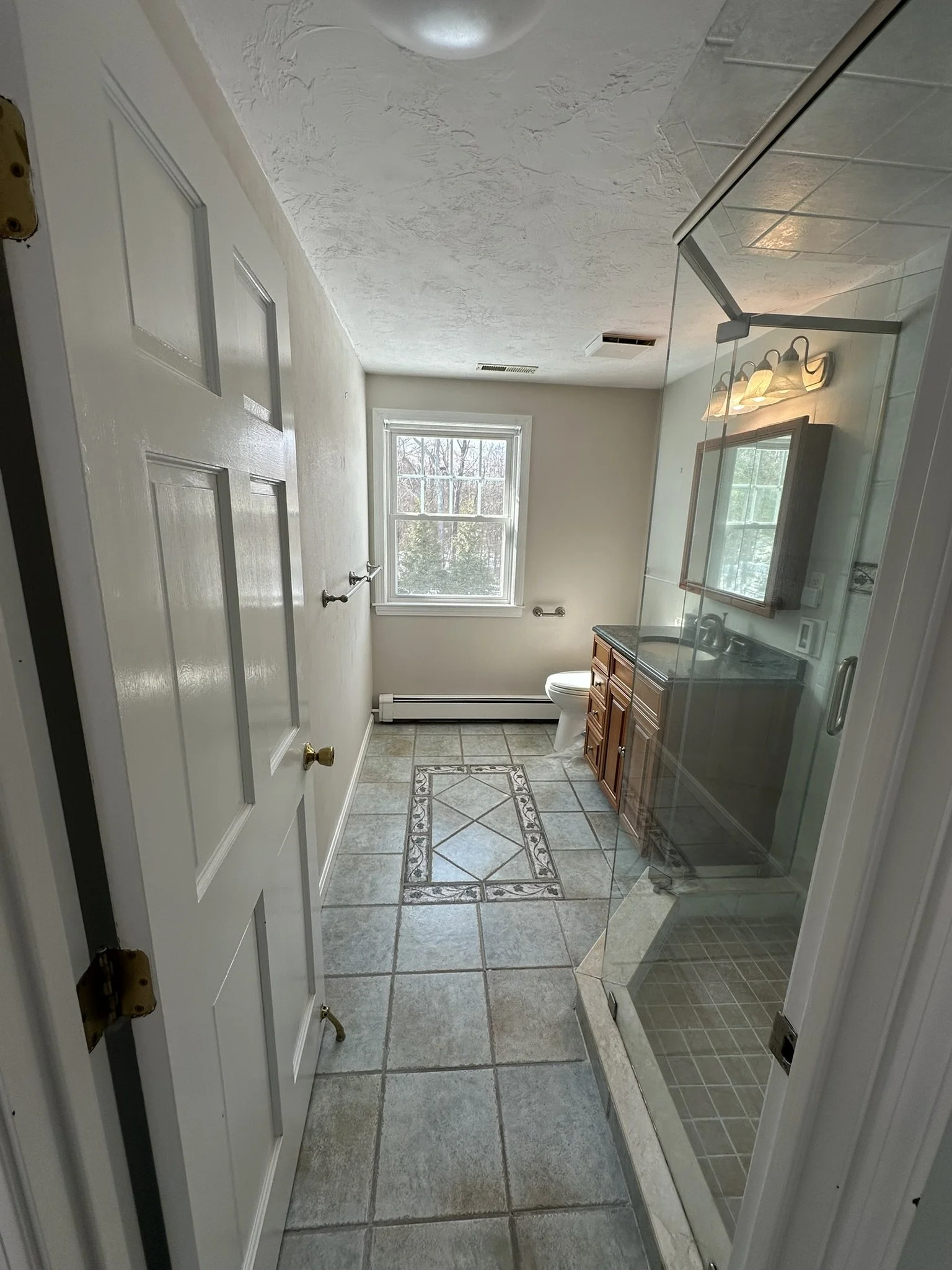 Bathroom before renovation with existing wood vanity and tile