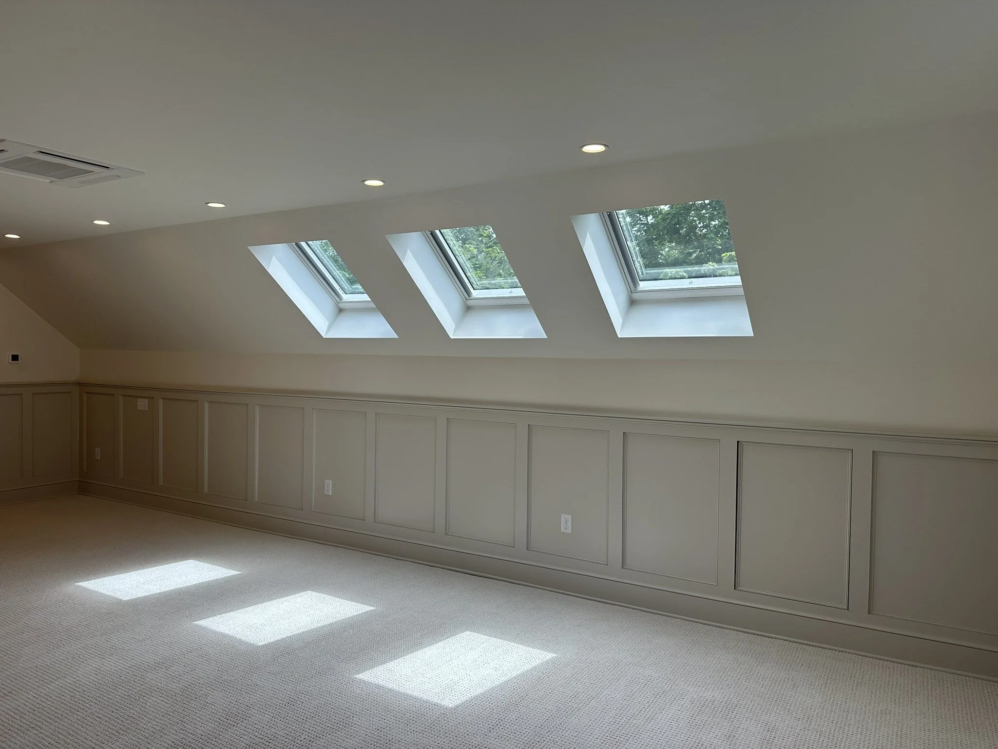 Custom paneled attic knee wall beneath three skylights