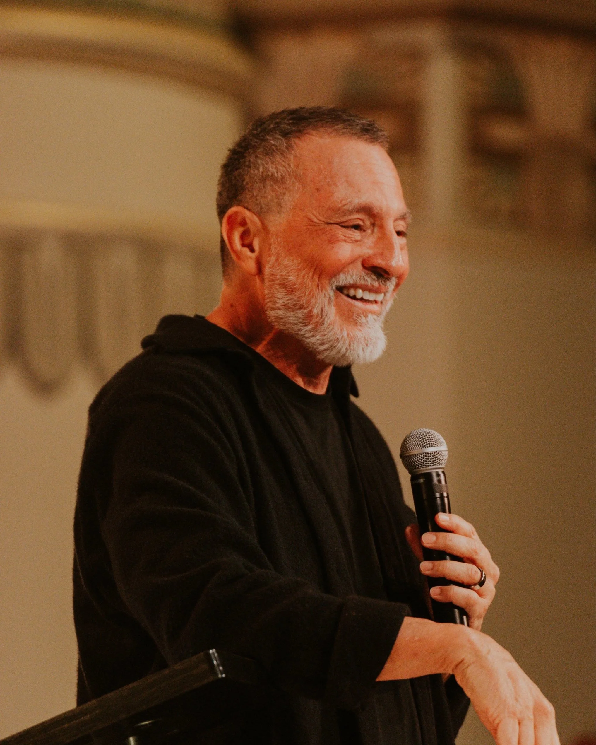 Erwin Raphael McManus smiling with a microphone in warm light